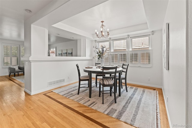 dining room featuring hardwood / wood-style flooring, baseboards, a chandelier, and a tray ceiling