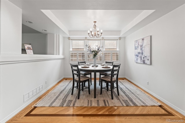 dining space featuring a chandelier, baseboards, and wood finished floors