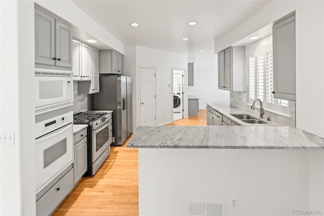 kitchen featuring appliances with stainless steel finishes, a sink, gray cabinets, decorative backsplash, and recessed lighting