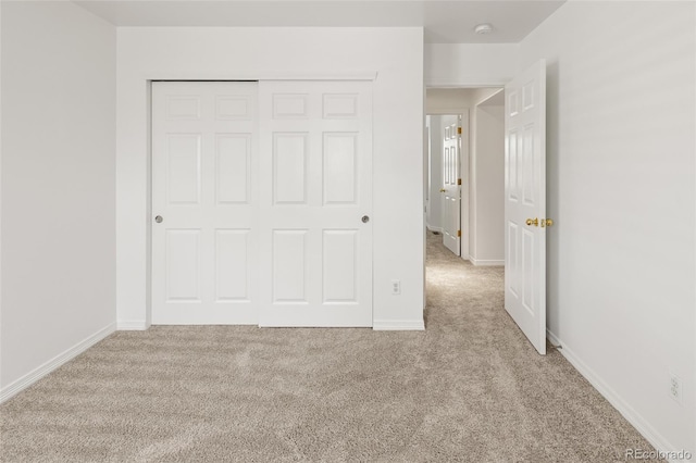 unfurnished bedroom with carpet flooring, a closet, and baseboards