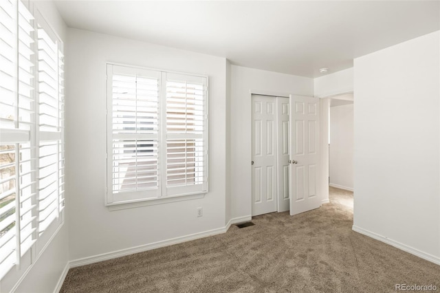 unfurnished bedroom with multiple windows, carpet flooring, and baseboards