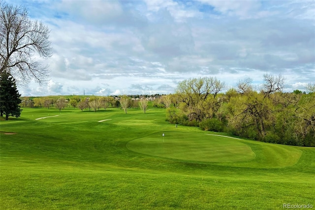 surrounding community featuring view of golf course, a lawn, and an area to practice putting