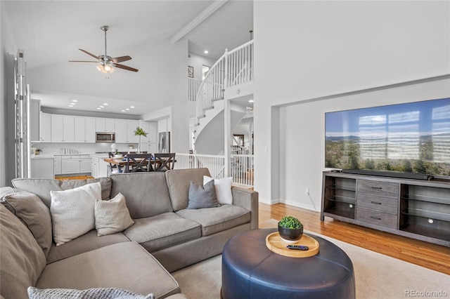16862 W 65th Cir, Arvada, CO 80007 - living area featuring high vaulted ceiling, ceiling fan, light wood-style floors, stairs, and beam ceiling