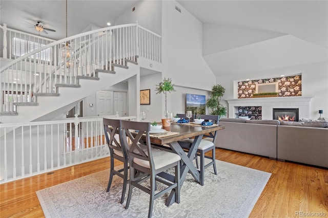 16862 W 65th Cir, Arvada, CO 80007 - dining area with high vaulted ceiling, ceiling fan, a glass covered fireplace, wood finished floors, and stairway