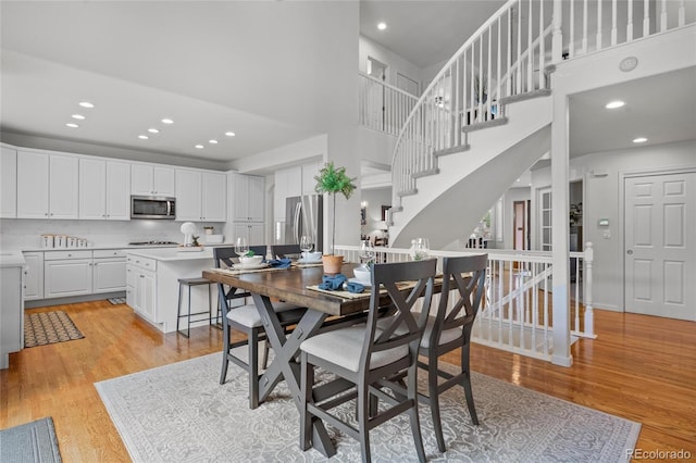 16862 W 65th Cir, Arvada, CO 80007 - dining space featuring a towering ceiling, light wood-type flooring, recessed lighting, and stairs
