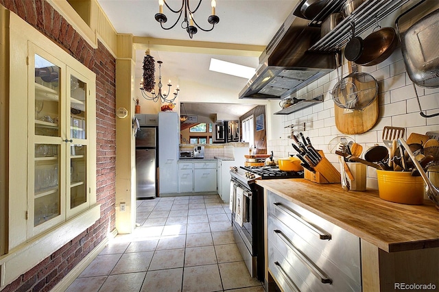 kitchen with light tile patterned floors, an inviting chandelier, appliances with stainless steel finishes, custom exhaust hood, and tasteful backsplash