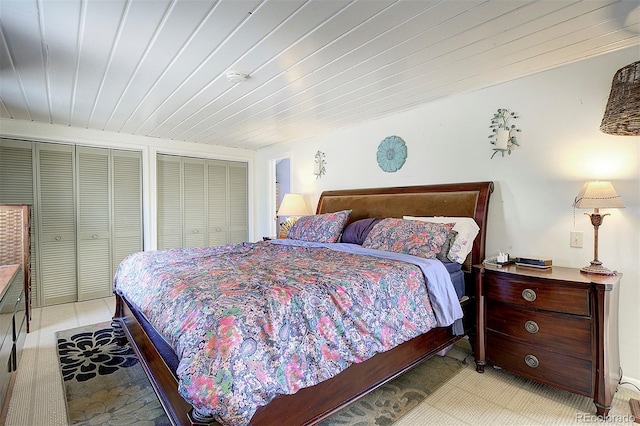 bedroom featuring wood ceiling and multiple closets