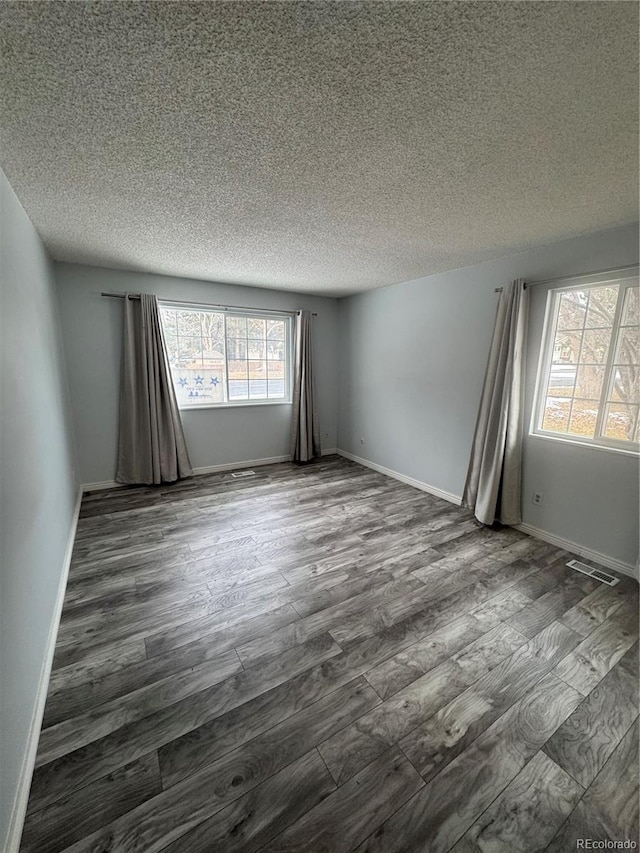 spare room with a textured ceiling and dark hardwood / wood-style floors