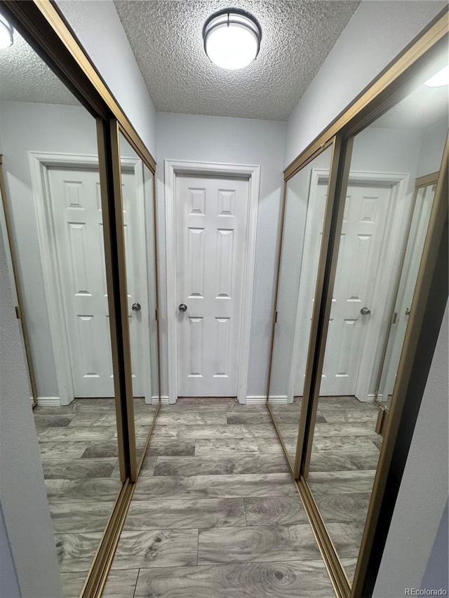 hallway with a textured ceiling and hardwood / wood-style flooring