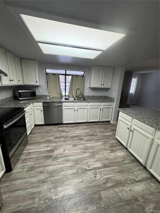 kitchen featuring sink, appliances with stainless steel finishes, light hardwood / wood-style flooring, and white cabinetry