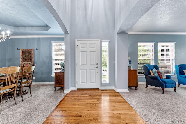 foyer entrance featuring ornamental molding, a textured ceiling, and light wood-type flooring