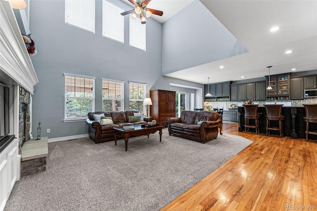 living room featuring a stone fireplace, ceiling fan, and light wood-type flooring