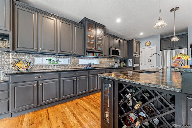 kitchen featuring pendant lighting, sink, backsplash, stainless steel appliances, and dark stone counters