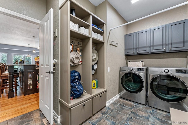 clothes washing area with cabinets, separate washer and dryer, and a textured ceiling