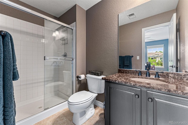 bathroom featuring toilet, a textured ceiling, vanity, a shower with door, and tile patterned flooring