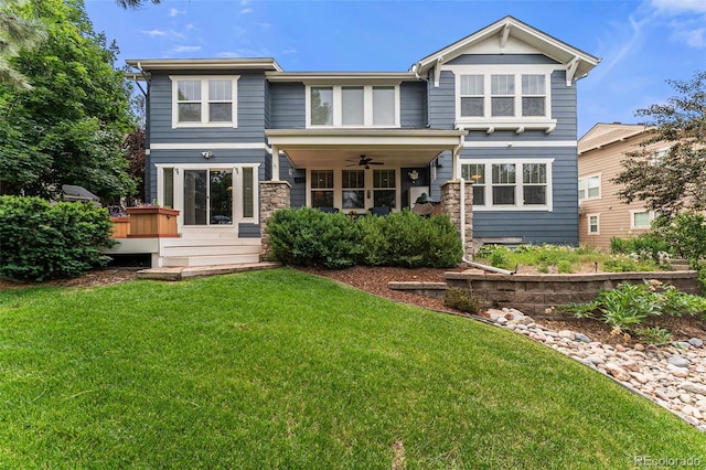 rear view of house featuring ceiling fan, a jacuzzi, and a lawn