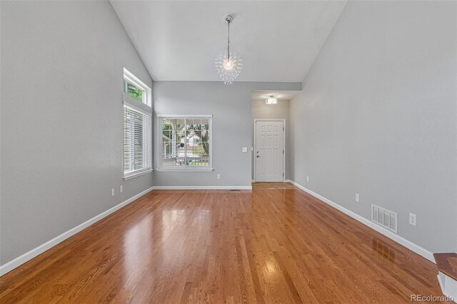 spare room with vaulted ceiling, a chandelier, and wood-type flooring