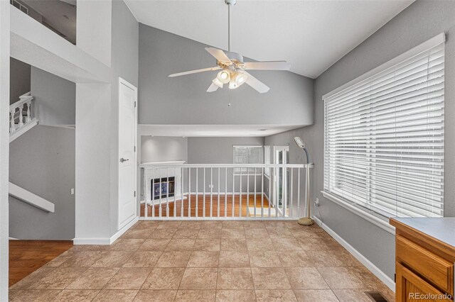 empty room with light tile patterned floors, a healthy amount of sunlight, ceiling fan, and lofted ceiling