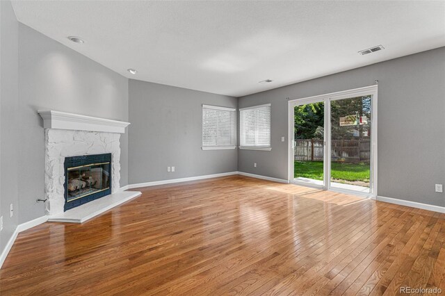 unfurnished living room with a stone fireplace and wood-type flooring