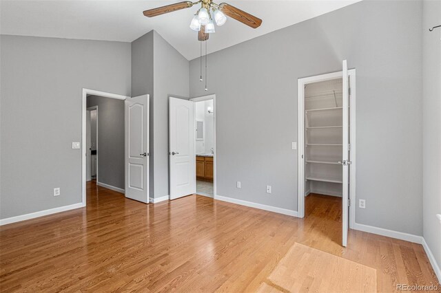 unfurnished bedroom featuring a spacious closet, a closet, ceiling fan, and hardwood / wood-style flooring