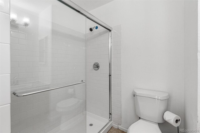 bathroom with toilet and a shower with shower door