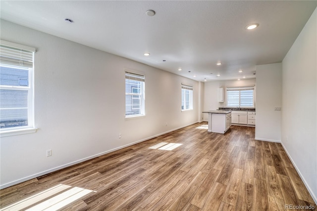 unfurnished living room with sink, plenty of natural light, and light wood-type flooring