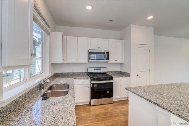 kitchen with light stone countertops, sink, white cabinets, and stainless steel appliances