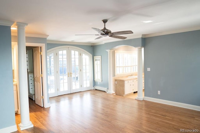 empty room with baseboard heating, french doors, a ceiling fan, ornate columns, and light wood-type flooring