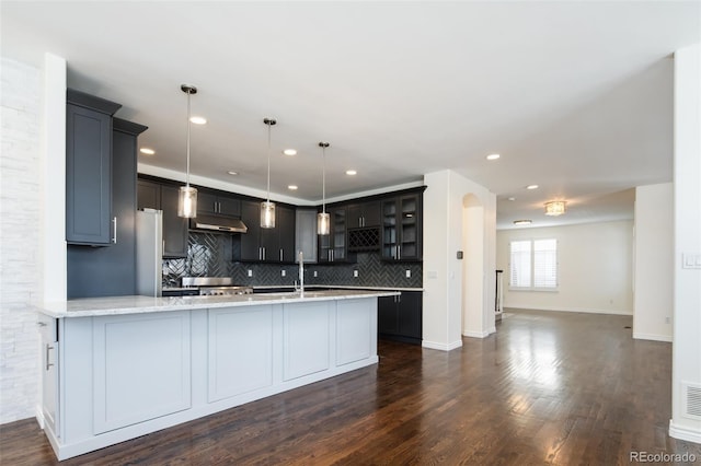 kitchen featuring light stone countertops, sink, tasteful backsplash, dark hardwood / wood-style flooring, and decorative light fixtures