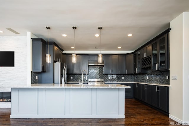 kitchen featuring light stone countertops, sink, dark hardwood / wood-style floors, stainless steel refrigerator with ice dispenser, and decorative light fixtures