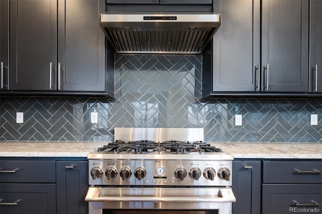 kitchen with high end range, tasteful backsplash, light stone counters, and wall chimney range hood