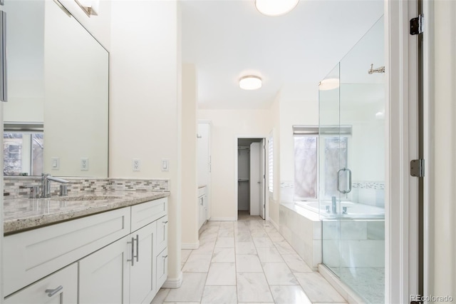 bathroom featuring plus walk in shower, decorative backsplash, and vanity