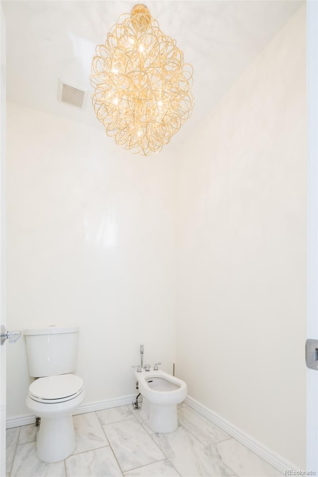 bathroom featuring toilet, a bidet, and an inviting chandelier