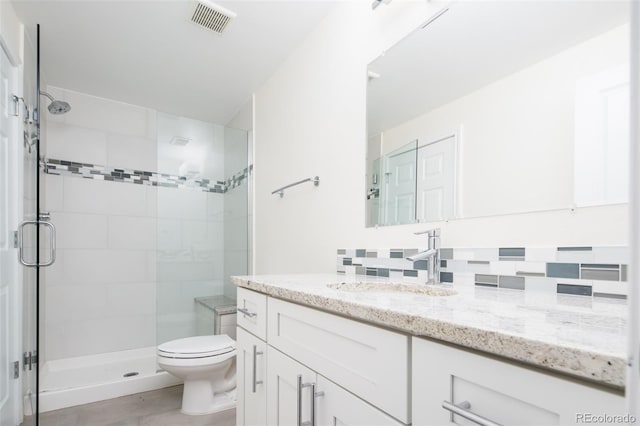 bathroom featuring decorative backsplash, vanity, a shower with shower door, and toilet