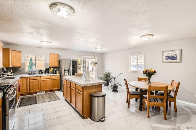 kitchen with a center island, sink, hanging light fixtures, decorative backsplash, and stainless steel appliances