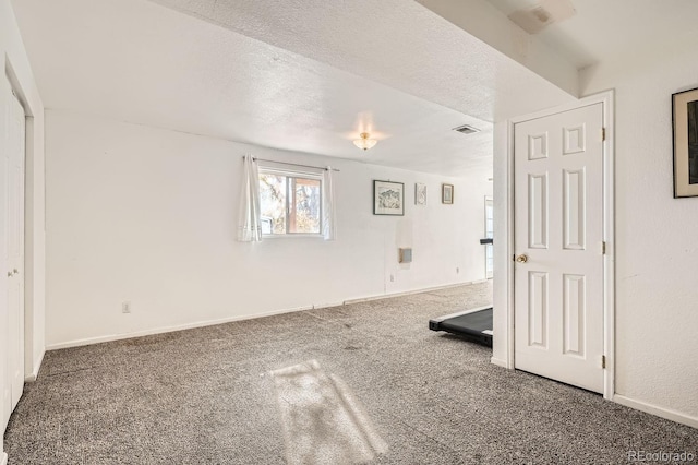 carpeted empty room featuring a textured ceiling