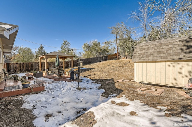 yard layered in snow with a gazebo and a storage shed