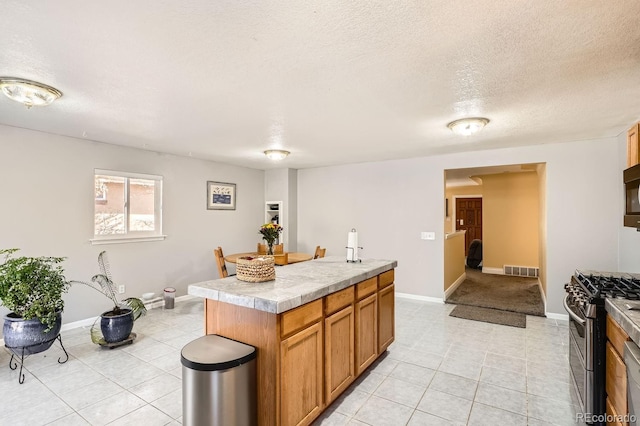 kitchen with stainless steel range with gas cooktop, a center island, light tile patterned floors, and a textured ceiling