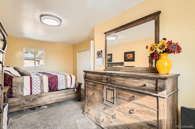 carpeted bedroom with a textured ceiling and a closet