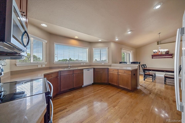 kitchen with dishwasher, stove, vaulted ceiling, decorative light fixtures, and light hardwood / wood-style floors