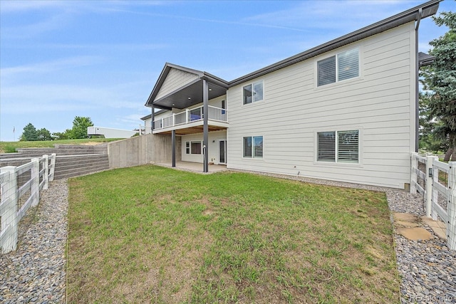 back of property featuring a lawn, a balcony, and a patio