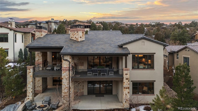 back of property featuring a tiled roof, a patio, a balcony, and stucco siding