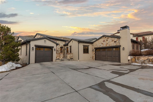 view of front facade featuring a tile roof, stucco siding, concrete driveway, an attached garage, and stone siding