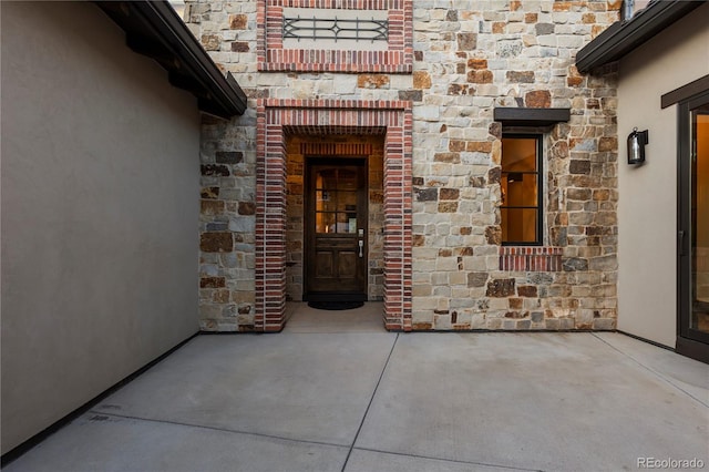 entrance to property featuring stone siding and stucco siding