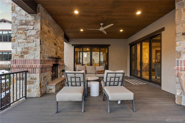 deck with ceiling fan and an outdoor living space with a fireplace