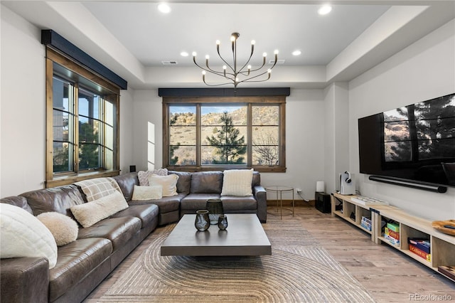 living room featuring visible vents, wood finished floors, an inviting chandelier, a tray ceiling, and recessed lighting