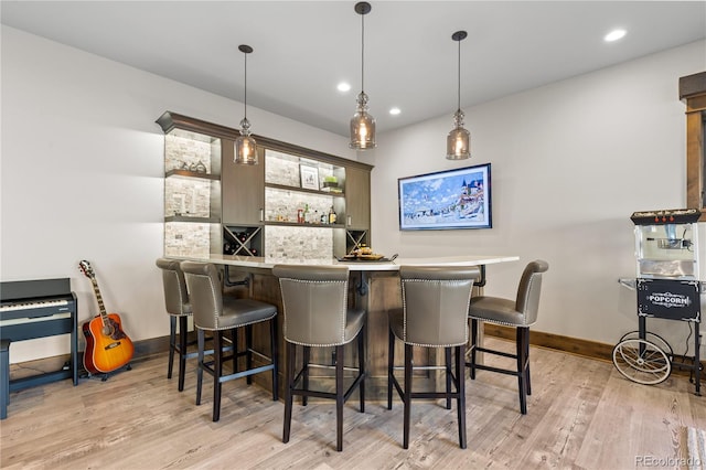 bar with a dry bar, recessed lighting, hanging light fixtures, light wood-style floors, and baseboards