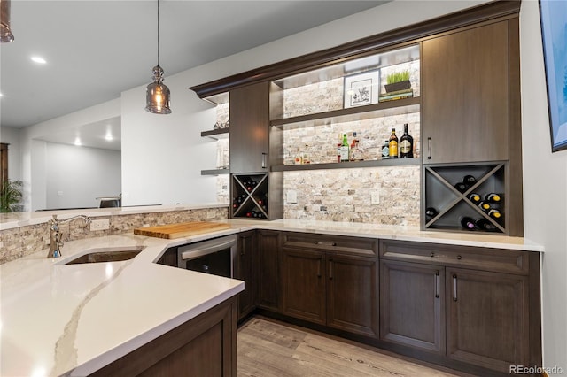 kitchen featuring light wood-style flooring, a sink, dark brown cabinets, hanging light fixtures, and open shelves