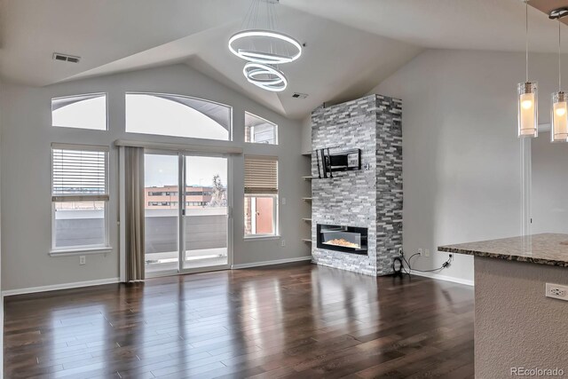 14251 E 1st Dr Unit 308, Aurora, CO 80011 - unfurnished living room featuring vaulted ceiling, a stone fireplace, dark wood finished floors, a chandelier, and baseboards