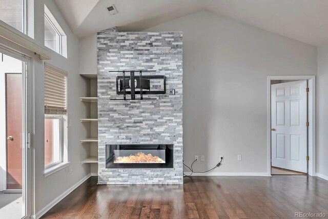 14251 E 1st Dr Unit 308, Aurora, CO 80011 - unfurnished living room featuring lofted ceiling, wood finished floors, plenty of natural light, built in shelves, and a stone fireplace